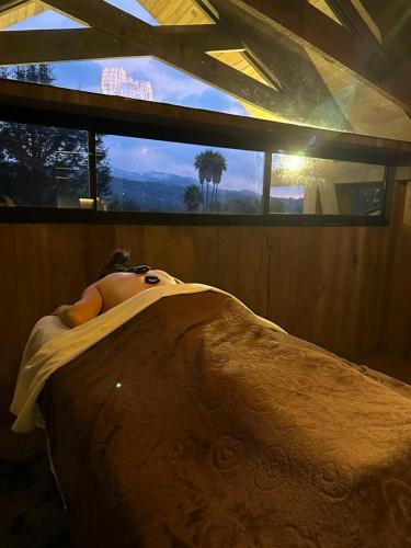 a man laying in a bed in front of a window at El Lugar del que te hable Hotel Boutique in Valle de Bravo
