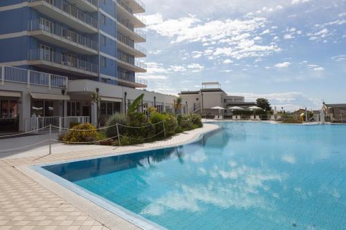 a large swimming pool in front of a building at Ai Pozzi Village Resort & SPA in Loano