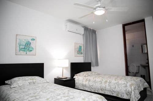 a bedroom with two beds and a ceiling fan at Residenciales H1 & H2 - Breakfast & Room Service - Airport close in Santiago de los Caballeros