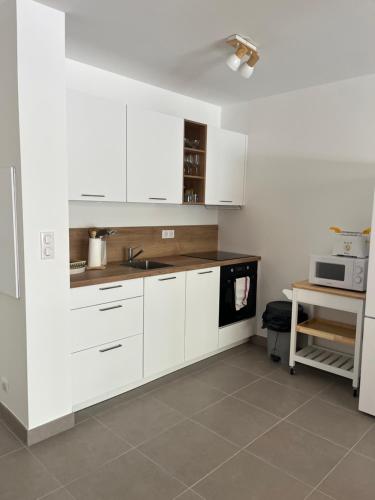 - une cuisine avec des placards blancs, un évier et une table dans l'établissement Porto Vecchio Sam, à Porto-Vecchio