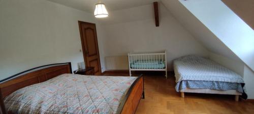 リボーヴィレにあるLA FERME DES PERLES NOIRESのベッドルーム1室(ベッド1台、ベビーベッド1台付)