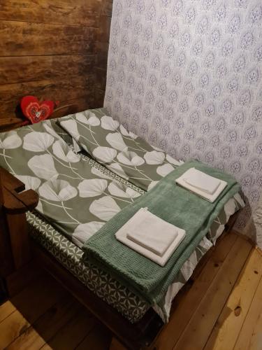 a bed with a green blanket and two napkins on it at Drinsko selo Ovčinja in Ovčinja