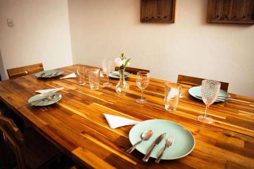 a wooden table with plates and silverware on it at Residenciales H1 & H2 - Breakfast & Room Service - Airport close in Santiago de los Caballeros