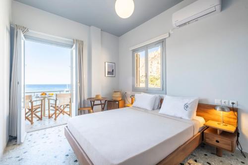 a bedroom with a bed and a view of the ocean at Akroyiali - Guesthouse in Gerolimenas