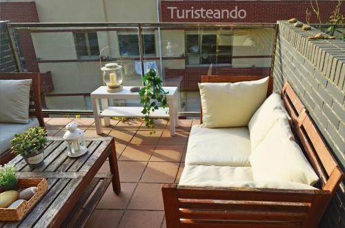 a patio with a couch and a table on a patio at La Casuca del Farolillo - con parking y terraza primera línea de playa in San Vicente de la Barquera