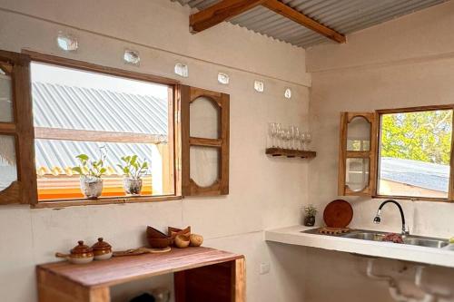 cocina con fregadero, 2 ventanas y barra en Casa Costa Salvaje, en El Gigante