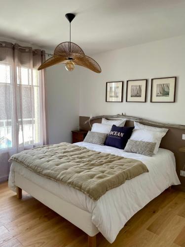 une chambre avec un grand lit et un lustre dans l'établissement Maison Neuve 3 Chambres avec jardin à 200m du port de la Teste, à La Teste-de-Buch