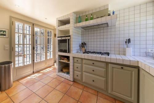 une cuisine avec des murs carrelés blancs et des comptoirs blancs dans l'établissement Mas de charme avec piscine, à Antibes