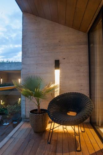 a chair and a potted plant on a wooden deck at El Lugar del que te hable Hotel Boutique in Valle de Bravo
