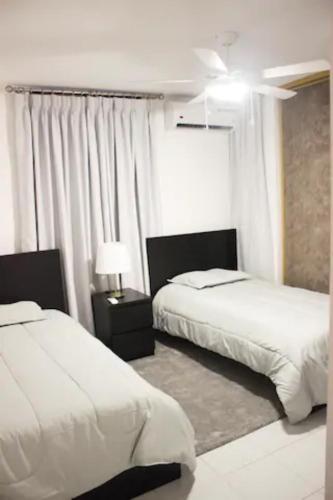 a bedroom with two beds and a ceiling fan at Residenciales H1 & H2 - Breakfast & Room Service - Airport close in Santiago de los Caballeros