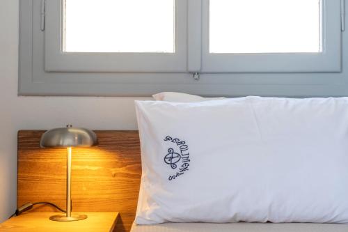 a bed with a pillow and a lamp on a table at Akroyiali - Guesthouse in Gerolimenas