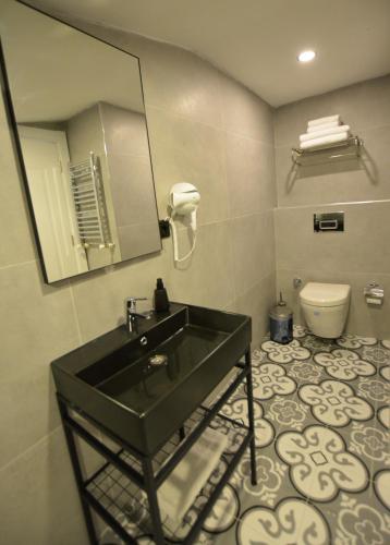a bathroom with a black sink and a toilet at Ağva Casa Rosa Bungalov Otel in Sile