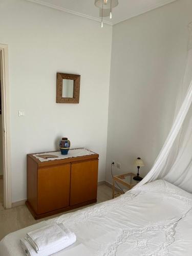 a white bedroom with a bed and a mirror at Seaside apartment away from the city- Oropos, Attiki in Oropós