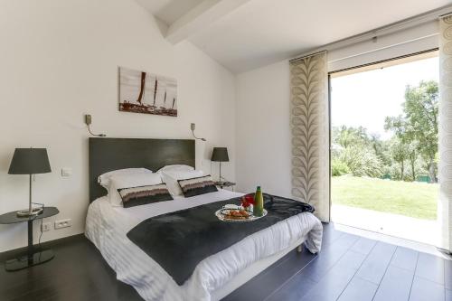 une chambre avec un grand lit et une grande fenêtre dans l'établissement Villa Annapurna, à Grimaud