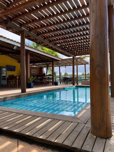 a swimming pool under a wooden pergola at Casa da praia amarela in Camaçari