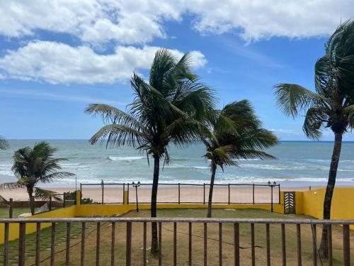 two palm trees on a beach with the ocean at Casa da praia amarela in Camaçari