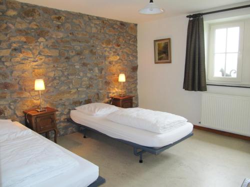 1 dormitorio con 2 camas y pared de piedra en Theux - La Reid, en Theux