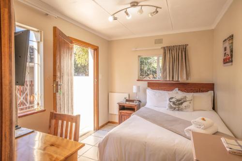 a bedroom with a bed and a desk with a laptop at 1-on-Ross in Grahamstown