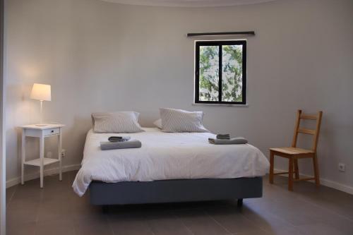 a bedroom with a bed with a window and a chair at Casas da Praia in Manta Rota