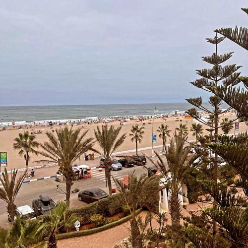 a view of a beach with cars and palm trees at Garden Beach 2 sidi rahal in Sidi Rahal