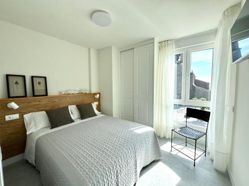 a white bedroom with a bed and a window at Apartamento Calas in Noja