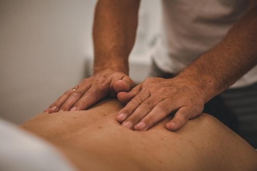 a man with his hands on the back of a patient at Hotel Metzgerwirt in Kirchberg in Tirol