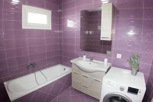 a purple bathroom with a sink and a toilet and a tub at Ammos Beach Apartment in Skaleta