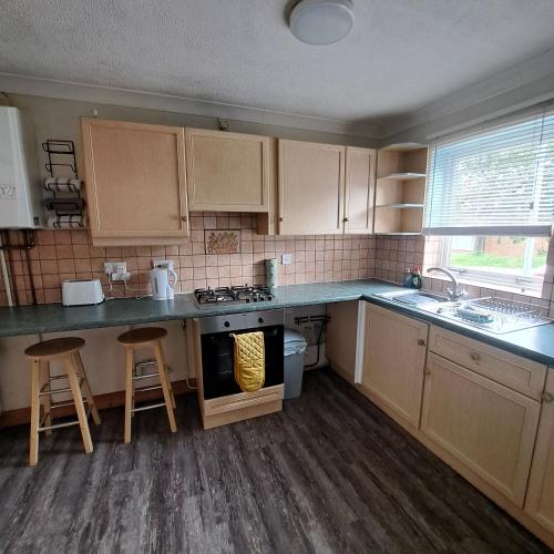 a kitchen with wooden cabinets and a stove top oven at Cute little 2 bed near Cambridge in Fenstanton