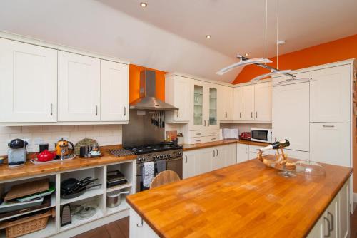 une cuisine avec des armoires blanches et un comptoir en bois dans l'établissement 4 Bedroom Apartment in Central Matlock with River Views, à Matlock