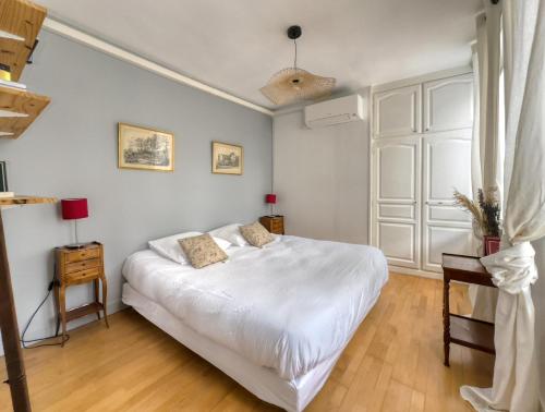 a bedroom with a large white bed and a wooden floor at Le Saint Lazare in Compiègne