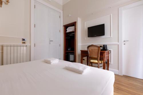 a bedroom with a bed and a desk and a television at Napolit'amo Hotel Principe in Naples