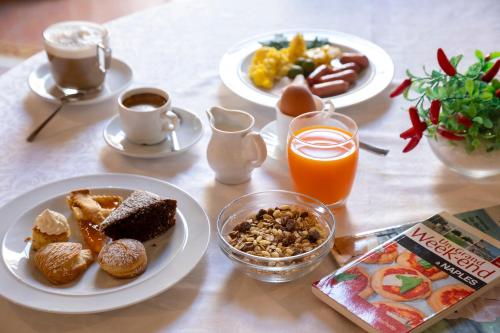 a table with plates of breakfast food and a book at Napolit'amo Hotel Principe in Naples