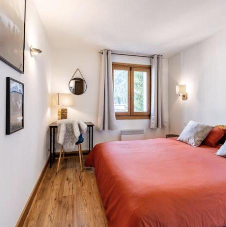 - une chambre avec un grand lit rouge et une fenêtre dans l'établissement Loriaz 12 - Appartement avec vue et piscine à deux pas du telecabine, à Vallorcine