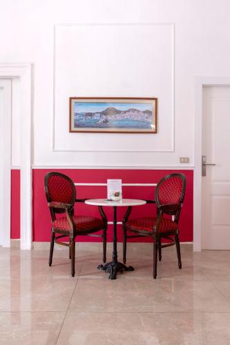 a table and chairs in a room with a red wall at Napolit'amo Hotel Principe in Naples