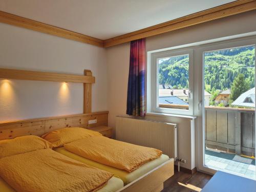 sypialnia z łóżkiem i dużym oknem w obiekcie Alpenpension Gastein w mieście Bad Gastein