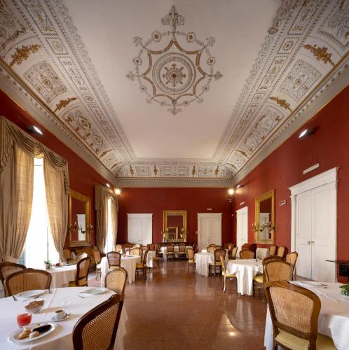 a dining room with tables and chairs and a ceiling at Napolit'amo Hotel Principe in Naples