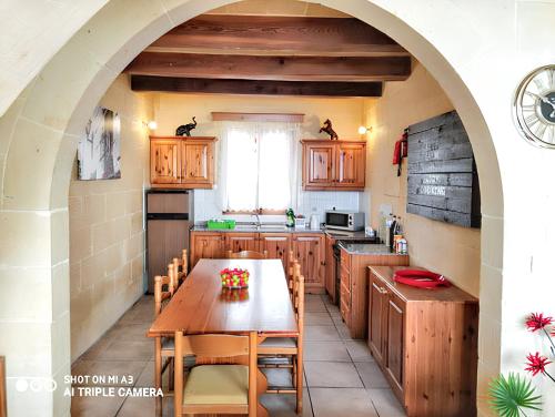 una cucina con tavolo in legno e arco di 3 bedrooms villa with sea view private pool and enclosed garden at Iz Zebbug a Qala