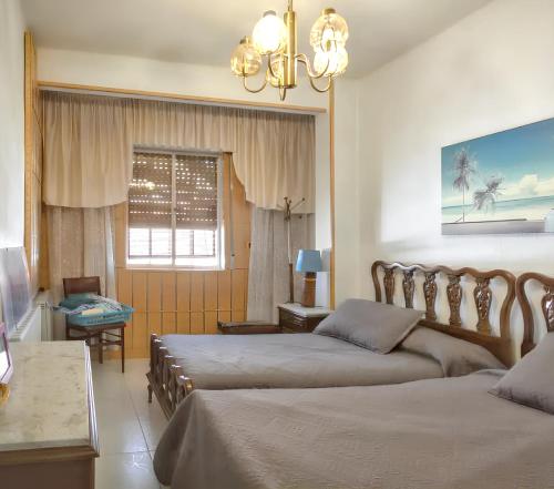 Vitigudino的住宿－3 bedrooms villa with shared pool and furnished terrace at Vitigudino，一间卧室设有两张床、一个窗户和一个吊灯。
