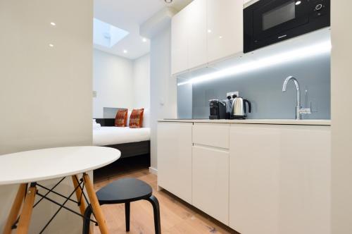 uma cozinha com um lavatório, uma mesa e uma cama em Regents Serviced Apartments by StayPrime em Londres