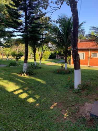 a group of trees in a park with a building at Chácara Recanto in Assis