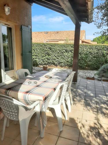 uma mesa branca e cadeiras num pátio em Maison de 2 chambres avec piscine partagee jardin clos et wifi a Eyguieres em Eyguières
