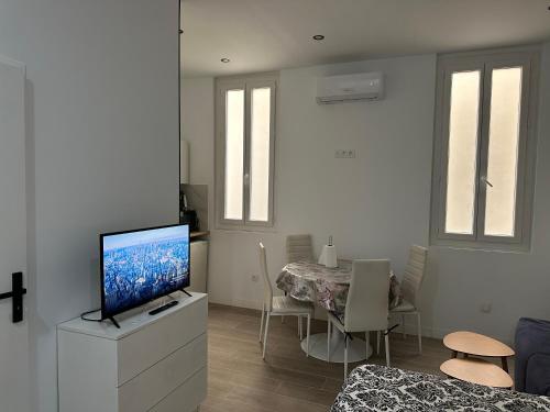 a living room with a television on a dresser with a dining table at Appartement vieux port marseille in Marseille