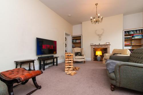 a living room with a couch and a tv at Spacious River View Retreat Near Peak District in Matlock