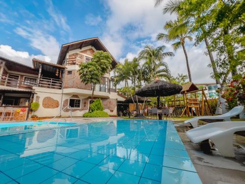 a pool in front of a house with palm trees at Pousada Pérola do Porto in Porto De Galinhas
