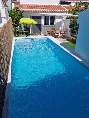 a blue swimming pool with a table and an umbrella at In Old Town With Pool in Tavira
