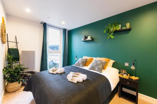 a green bedroom with a bed with towels on it at Amazing Flat-Parking available-By FabAccommodation in Cardiff
