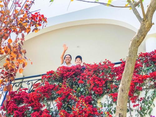 two people standing over a balcony with red flowers at Casa Hotel Mamaluna in Lunahuaná