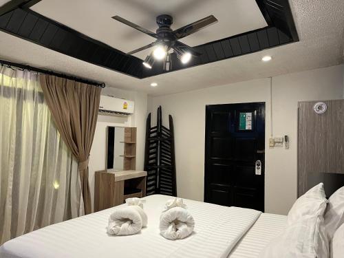 a bedroom with a bed with white sheets and a ceiling fan at Big Boys' Bed & Burger - Patong Beach in Patong Beach