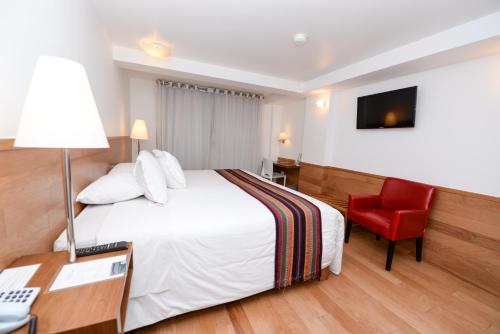 a hotel room with a bed and a red chair at Hotel Plaza de Armas Cusco in Cusco