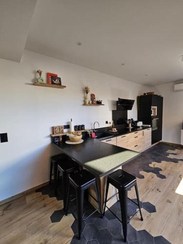 une cuisine avec une table noire et un réfrigérateur noir. dans l'établissement Maison proche des Calanques de la Côte Bleue, à Ensuès-la-Redonne